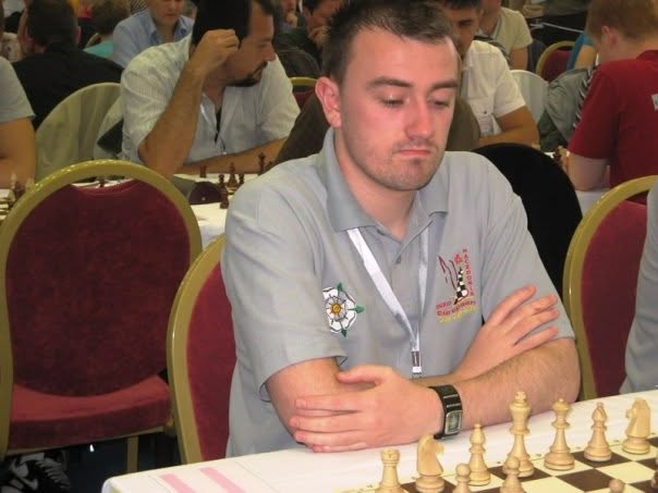 Me at the board in a packed international tournament hall in Ohrid, rows of other players and boards stretching away behind me.